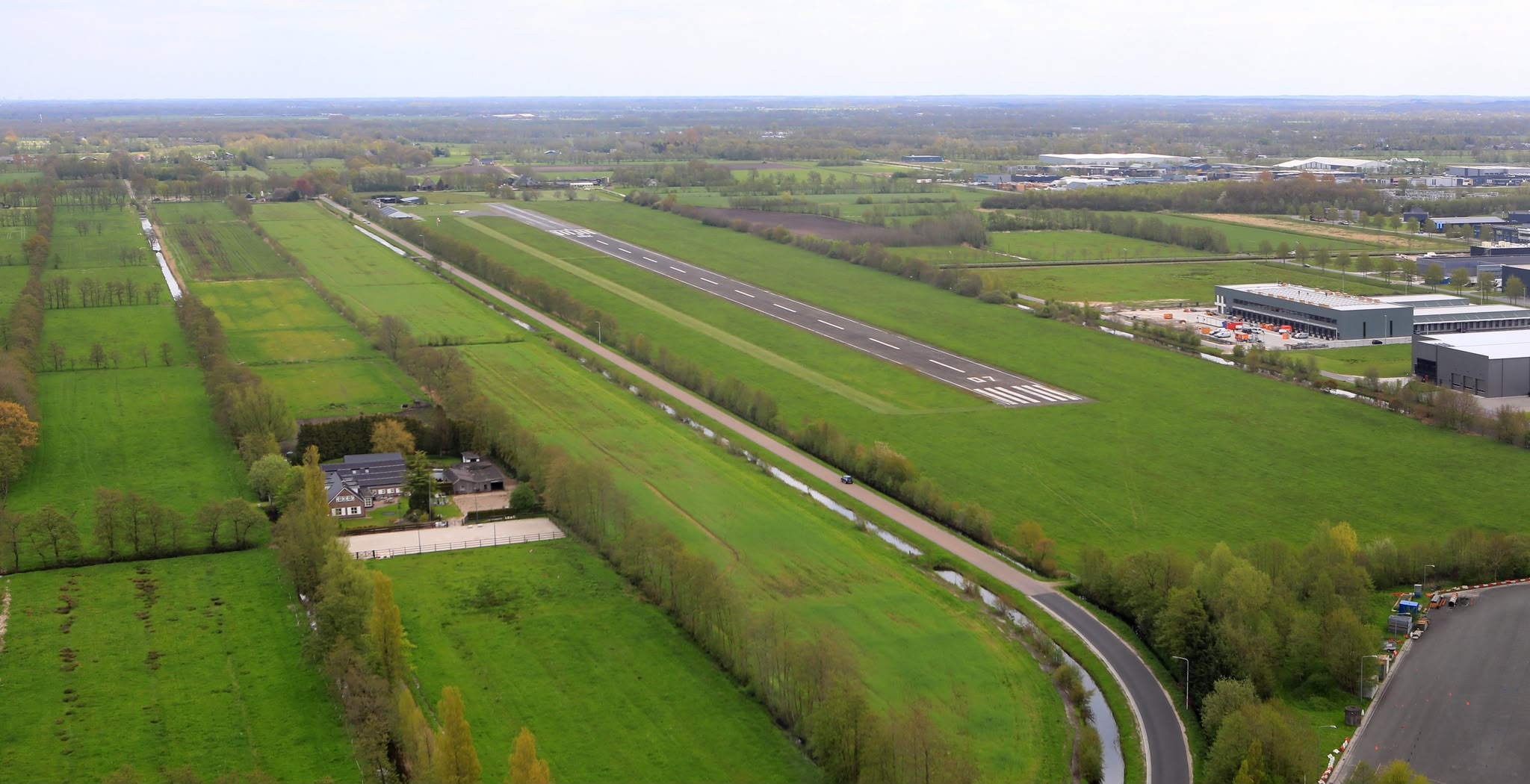 Luchtfoto van Drachten Airport met de start- en landingsbaan en omliggende bebouwing
